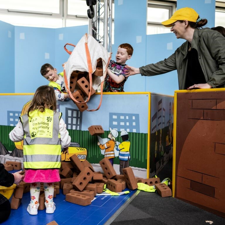 Two boys, a little girl and a woman tip out a bag of foam bricks