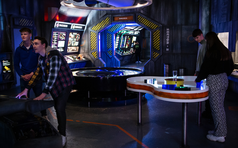 Four people interacting with space science exhibits