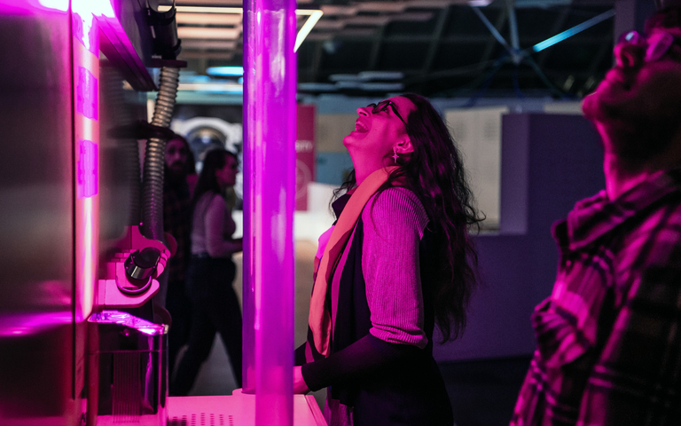 A woman laughing whilst looking up at a science exhibit