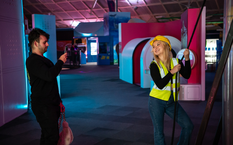 A girl posing for a photograph wearing a high visibility jacket and hard hat