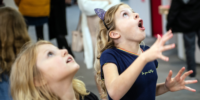 Two little girls look at the sky with amazed expressions on their faces