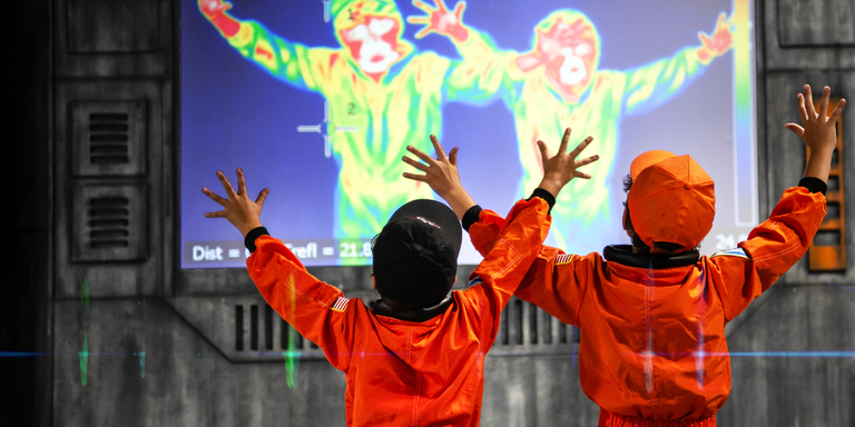 Two children in space jumpsuits play with a heat indicating exhibit