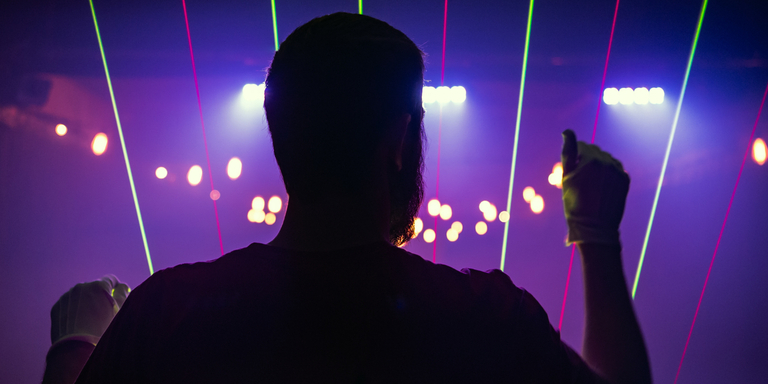 A man is silhouetted by laser light beams