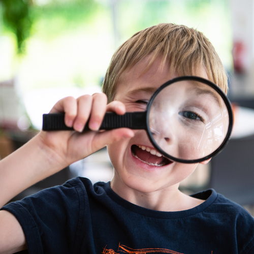 Boy holding up a magnifying glass to his eye