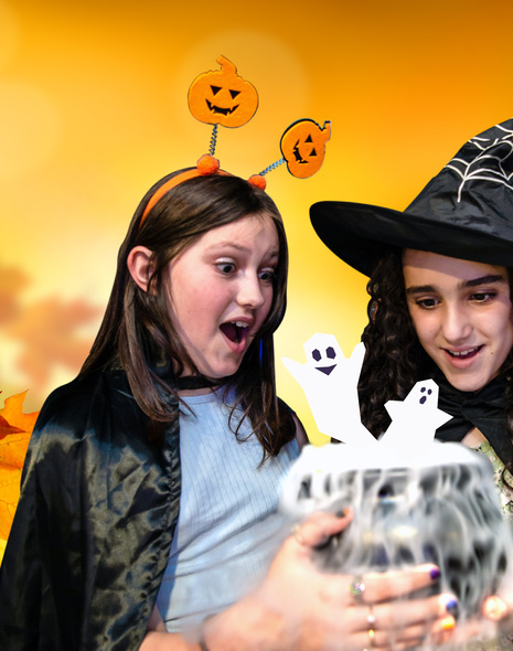 Two girls in Halloween costumes looking at a cauldron