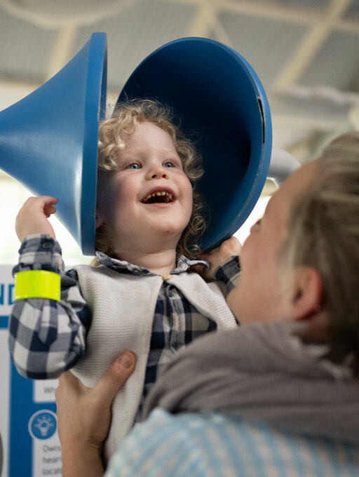 A little boy stares in wonder as he stretches some purple slime